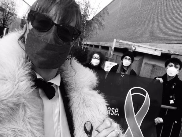 Protect the Heart of the Arts campaign members Protect the Heart of the Arts campaign members in black and white. One in foreground in tuxedo and mask. Three in background wearing respirator masks and holding banner.